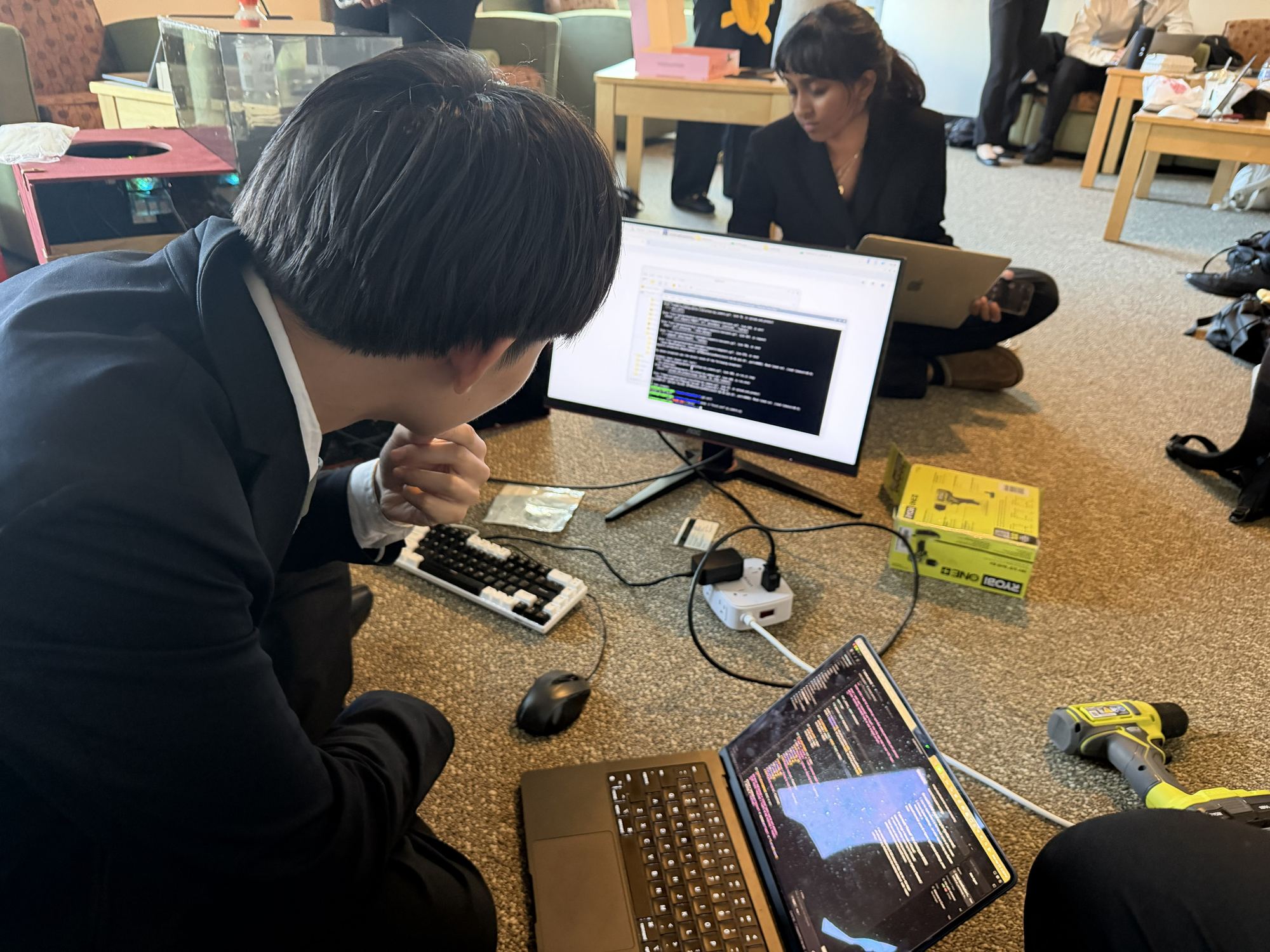 Team member at a laptop and monitor running the training script.