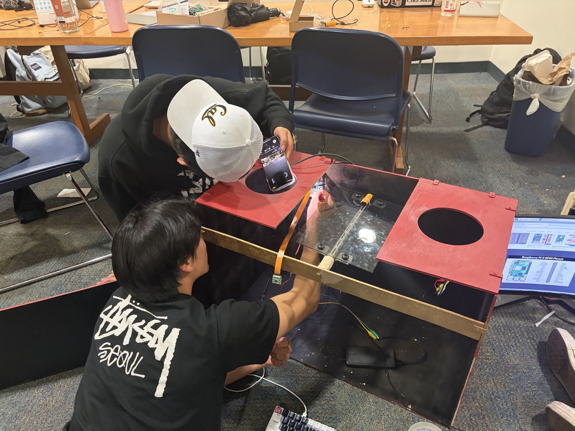 Two team members wiring the camera and electronics into the painted lid.